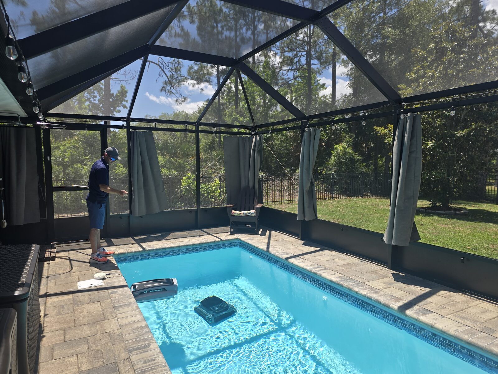 Contractor installing Privacy On Demand outdoor privacy curtains on a pool enclosure